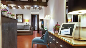 A modern hotel room with a wooden ceiling, a sofa, a desk with a lamp, and a welcome sign. - Stay U-nique Apartments Carretes (Barcelona)