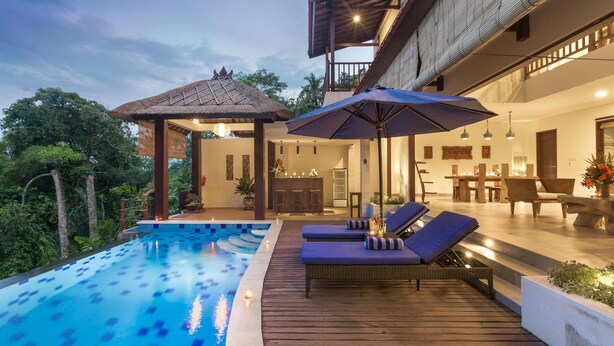 A modern outdoor pool area with lounge chairs and a thatched-roof structure.