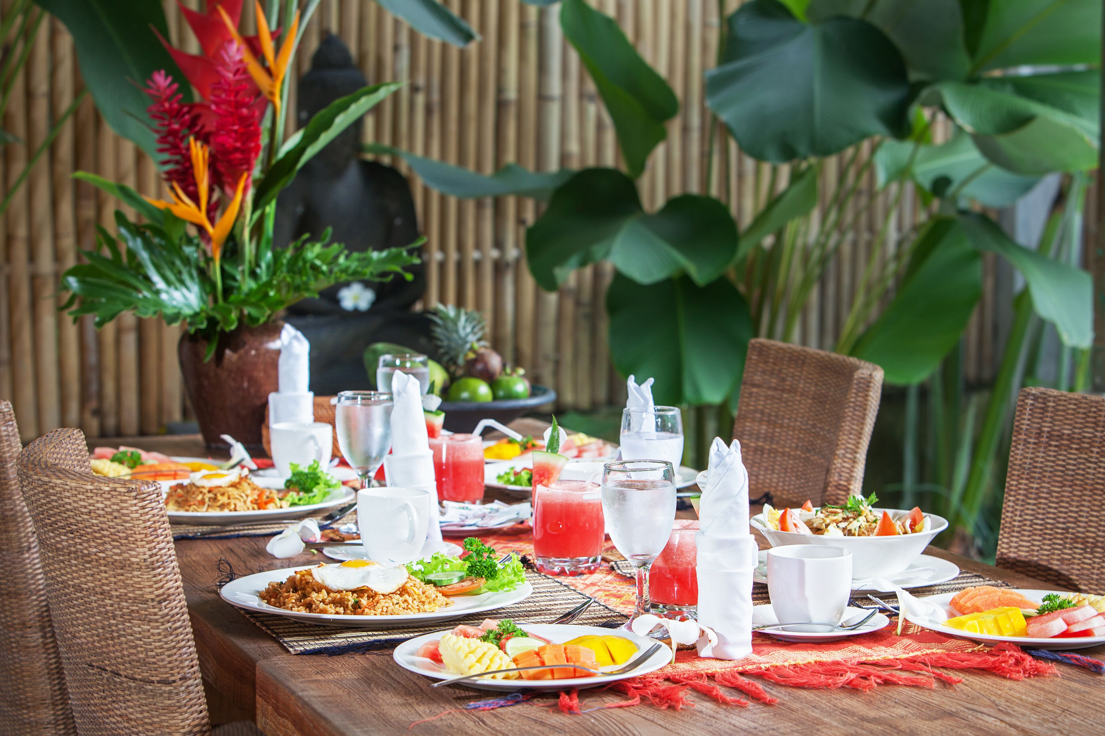 A table set for a meal with various dishes, drinks, and a potted plant.