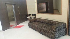 A modern lobby with a sofa, chairs, an elevator, and a large mirror. - Hotel Fujisan PWTC (Kuala Lumpur)