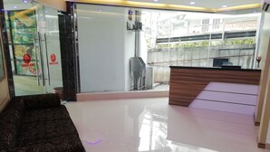 A modern reception area with a glass wall, a wooden reception desk, and a patterned sofa. - Hotel Fujisan PWTC (Kuala Lumpur)