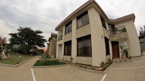 A modern two-story building with a flat roof, large windows, and a balcony. - Nandi Residence (Kigali)