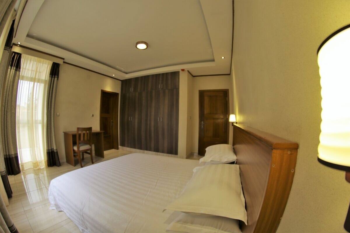 A hotel room with a large bed, a desk, and a wardrobe.