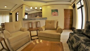 A living room with two sofas, a coffee table, and a kitchen area in the background. - Nandi Residence (Kigali)