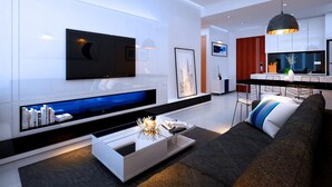 A modern living room with a flat-screen TV mounted on the wall, a built-in fireplace, a dining area with a kitchen in the background, and a large window. - Ami Splendid Luxury Royal (Ho Chi Minh City)