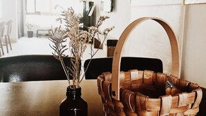 A wooden table with a dark glass vase and dried flowers, a woven basket, and a wooden cutting board. - Lin's Inn (Ruisui)