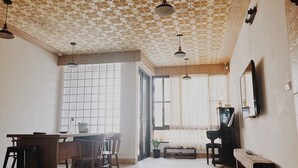 A dining area with a table and chairs, a piano, and a large window with a view. - Lin's Inn (Ruisui)