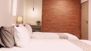 A bedroom with a bed, a bedside lamp, a hanging light fixture, and a brick accent wall. - Lin's Inn (Ruisui)