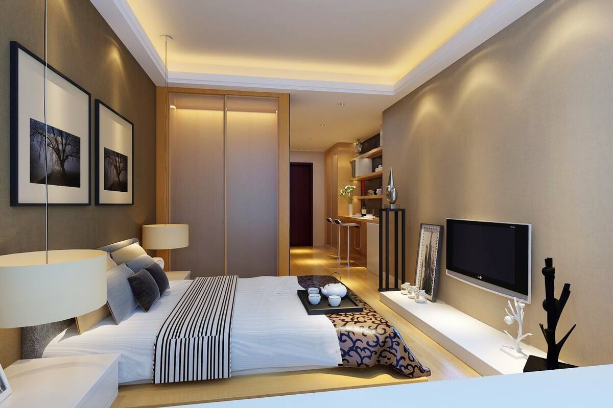 Una habitación de hotel moderna con una cama grande, lámparas de noche, un televisor de pantalla plana y una pequeña zona de estar con una mesa y sillas.