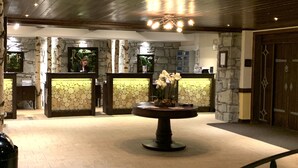 A lobby with stone walls, a reception desk, and a central round table with a vase of flowers.