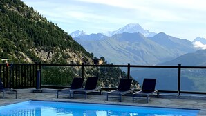 A pool with lounge chairs and a mountain view.