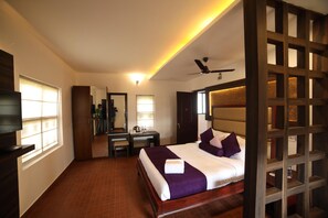 A hotel room with a bed, a desk, a chair, and a TV. - Contour Island Resort & Spa (Vythiri)