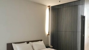 A modern hotel room with a large bed, a bedside table, and a black privacy screen. - T+ Premium Hotel (Alor Setar)