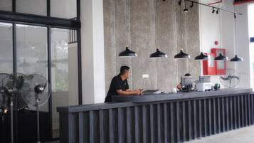 A reception desk with a modern design, featuring a black countertop, multiple black pendant lights, and a large window providing natural light.