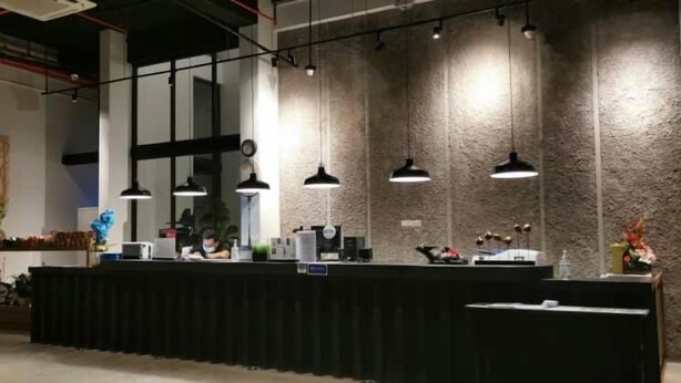 A reception area with a black counter, pendant lighting, and a stone-textured wall. - T+ Premium Hotel (Alor Setar)
