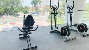 A gym with exercise equipment and a view of a street and buildings. - T+ Premium Hotel (Alor Setar)