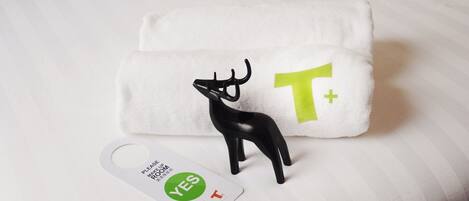 Une serviette blanche ornée d’un renne noir et d’un symbole vert « T+ », ainsi qu’une étiquette avec les mots « OUI » et « T » sur un fond blanc.