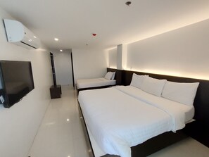 A modern hotel room with two single beds, a flat-screen TV, and a built-in air conditioning unit. - Top Star Hotel Tagum (Tagum)