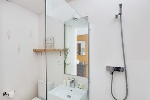 Une salle de bain moderne avec une paroi en verre, une douche, un lavabo et un miroir.