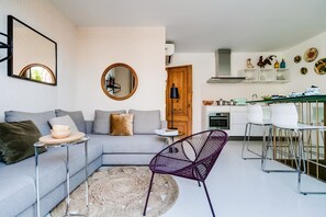 A modern living room with a sofa, a round mirror, a coffee table, and a purple chair.