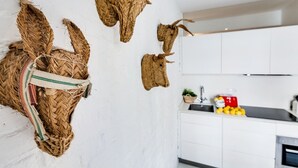 Eine Küche mit weißen Schränken, einem Spülbecken und einer Arbeitsplatte mit Zitronen und einem roten Behälter.