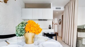 Ein Essbereich mit einem Tisch für vier Personen, einer Goldvase mit Blumen und einer weißen Ziegelwand.