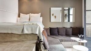Ein modernes Schlafzimmer mit einem großen Bett, einer grauen Couch und einem kleinen Tisch.