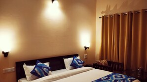 A hotel room with a bed, two wall-mounted lights, a window with curtains, and a bedside table with a lamp. - Hotel Vista (Nainital)