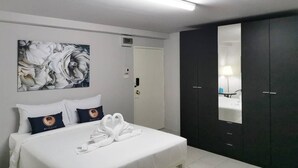 A hotel room with a bed, a large abstract painting, a wardrobe, and a mirror.