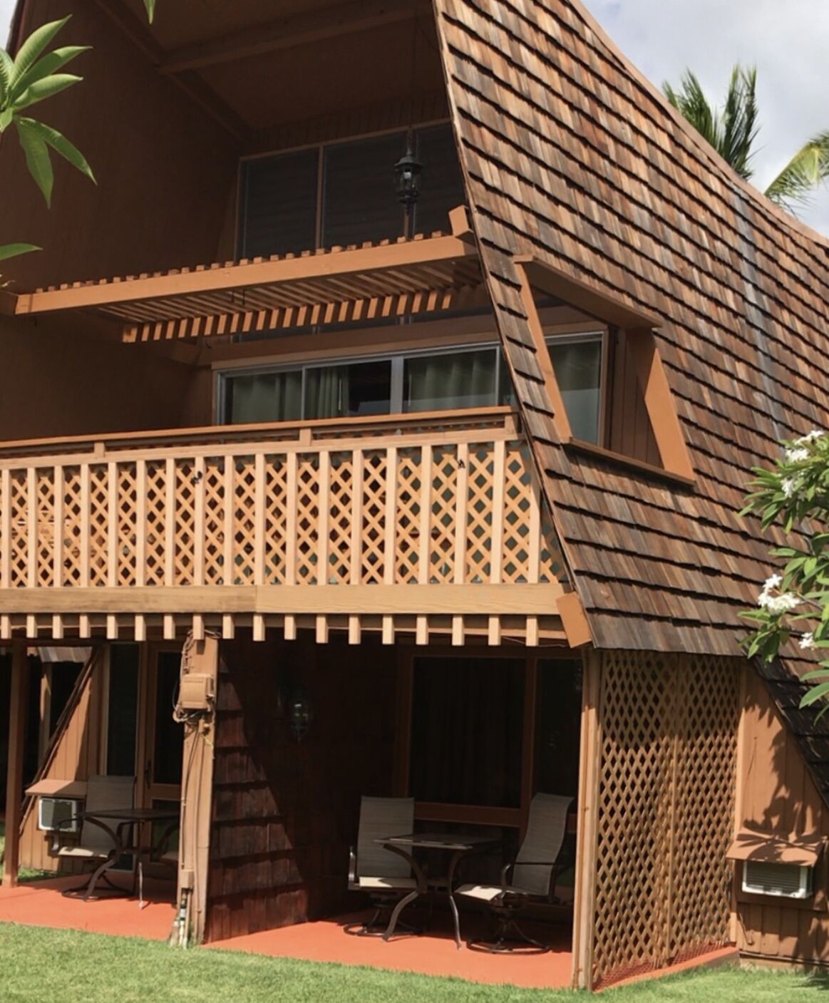 Una casa de madera de dos pisos con un balcón, mobiliario exterior y una pequeña mesa.