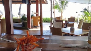 A dining table with a plate of food, a basket of fries, and a bottle of sauce.