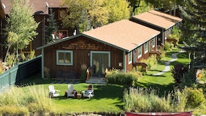 A lodge with a wooden exterior, a grassy front yard, and a boat on the water. - Outpost: Alpine Cottage Three (Jackson)