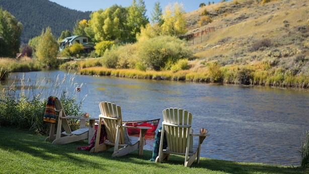 Two Adirondack chairs by a lake with a house in the background. - Outpost: Alpine Cottage Three (Jackson)
