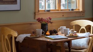 A dining area with a wooden table, chairs, and a window with a view of birch trees. - Outpost: Alpine Cottage Three (Jackson)