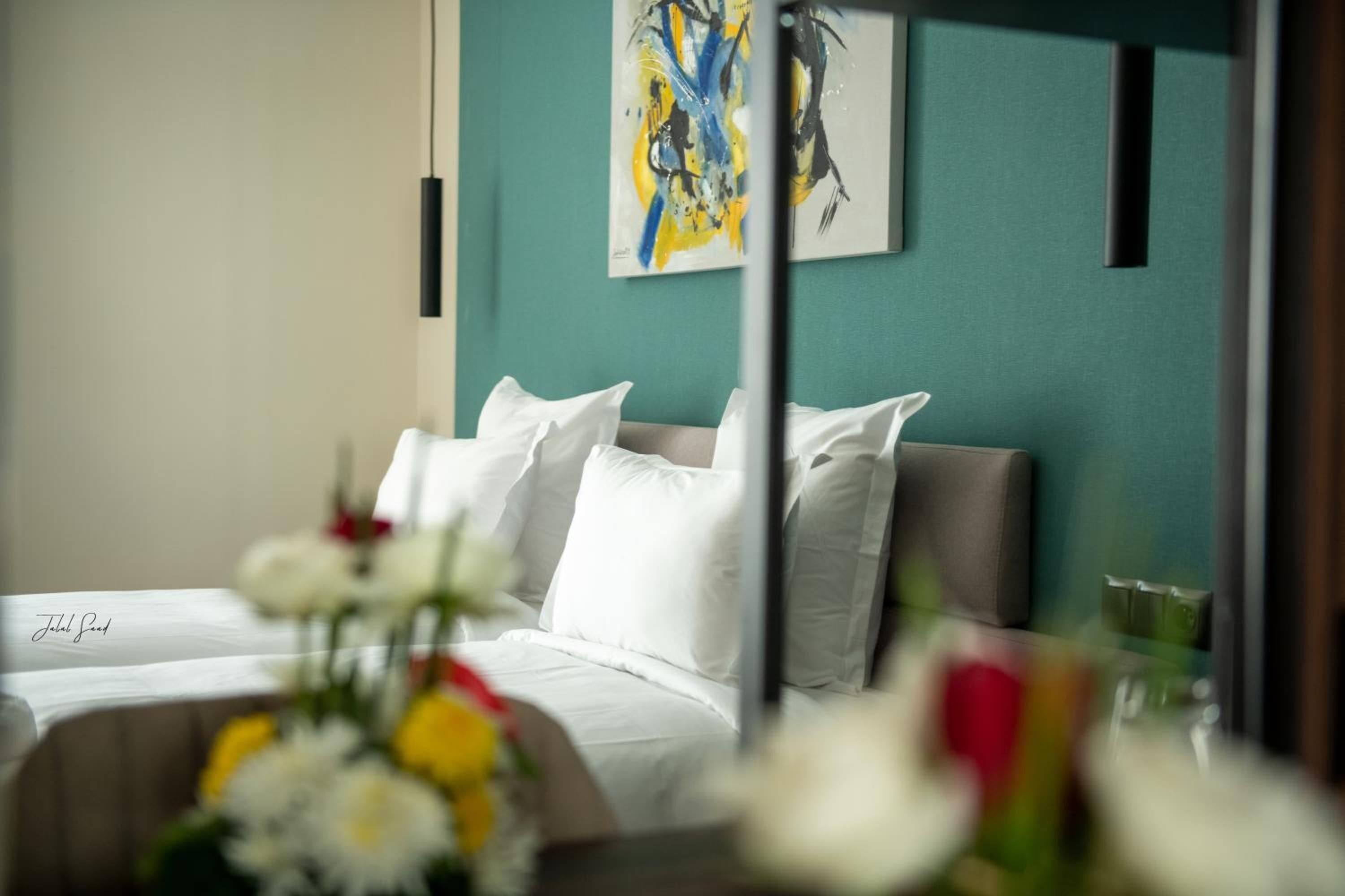 Une chambre d’hôtel avec un lit, du linge de lit blanc et un tableau accroché au mur.
