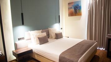 Quarto moderno com uma cama grande, mesas de cabeceira e um quadro na parede.
