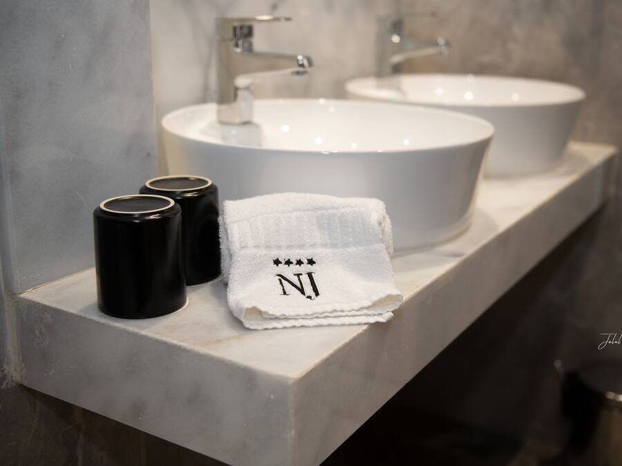 A bathroom vanity with two sinks, a towel, and two black containers.