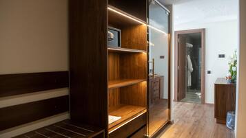 Un baño moderno con tocador de madera, cabina de ducha de vidrio y vestidor con estantes.