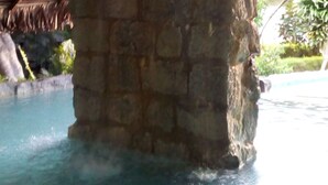 A stone structure partially submerged in water, with a thatched roof overhead. - Kintana Hotel (Nosy Be)