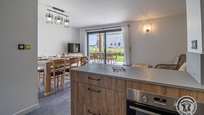 Une cuisine moderne dotée d’un îlot central, de meubles en bois et d’un coin repas avec des chaises et une table.