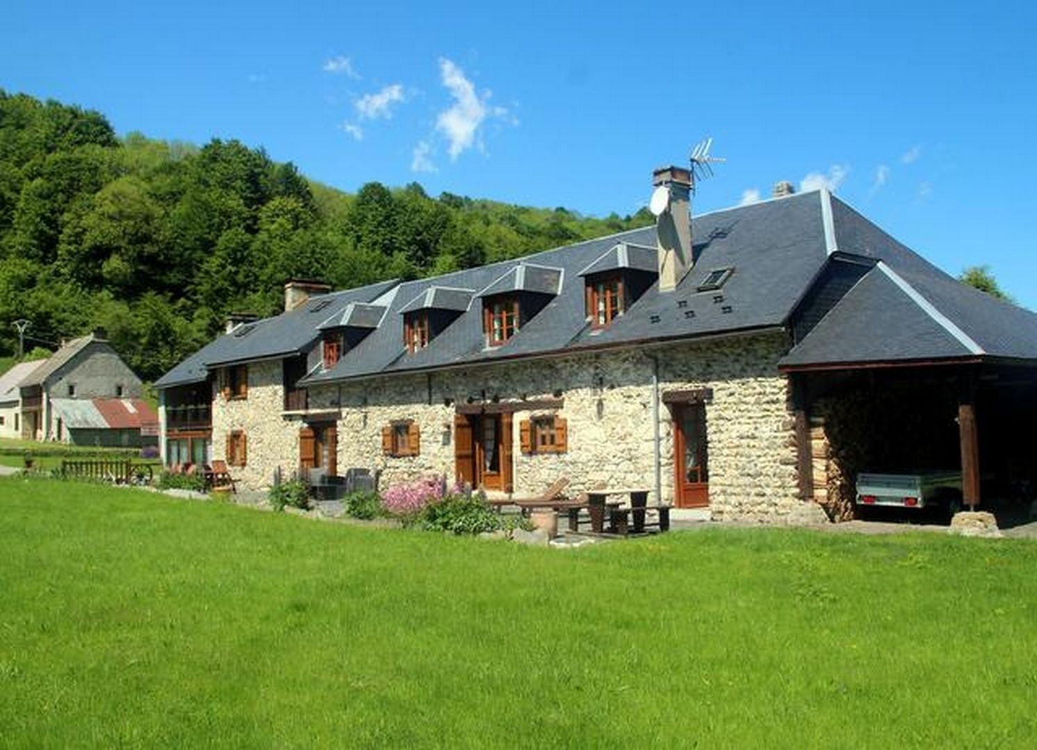 A stone building with multiple gabled roofs, a chimney, and a covered porch.