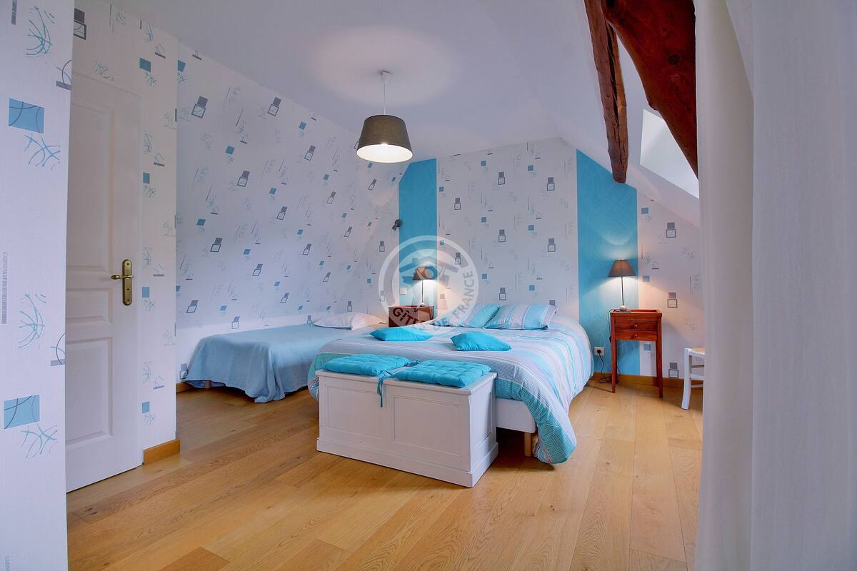 Ein Schlafzimmer mit zwei Betten, Holzboden und Wandpapier mit Muster.