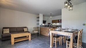 Un salon moderne avec un canapé, un banc en bois et une table à manger dressée pour quatre personnes.
