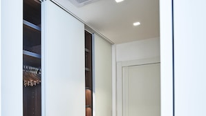 A hallway with a wooden floor, a white door, and a closet with a metal rack. - Lario Apartment (Como)