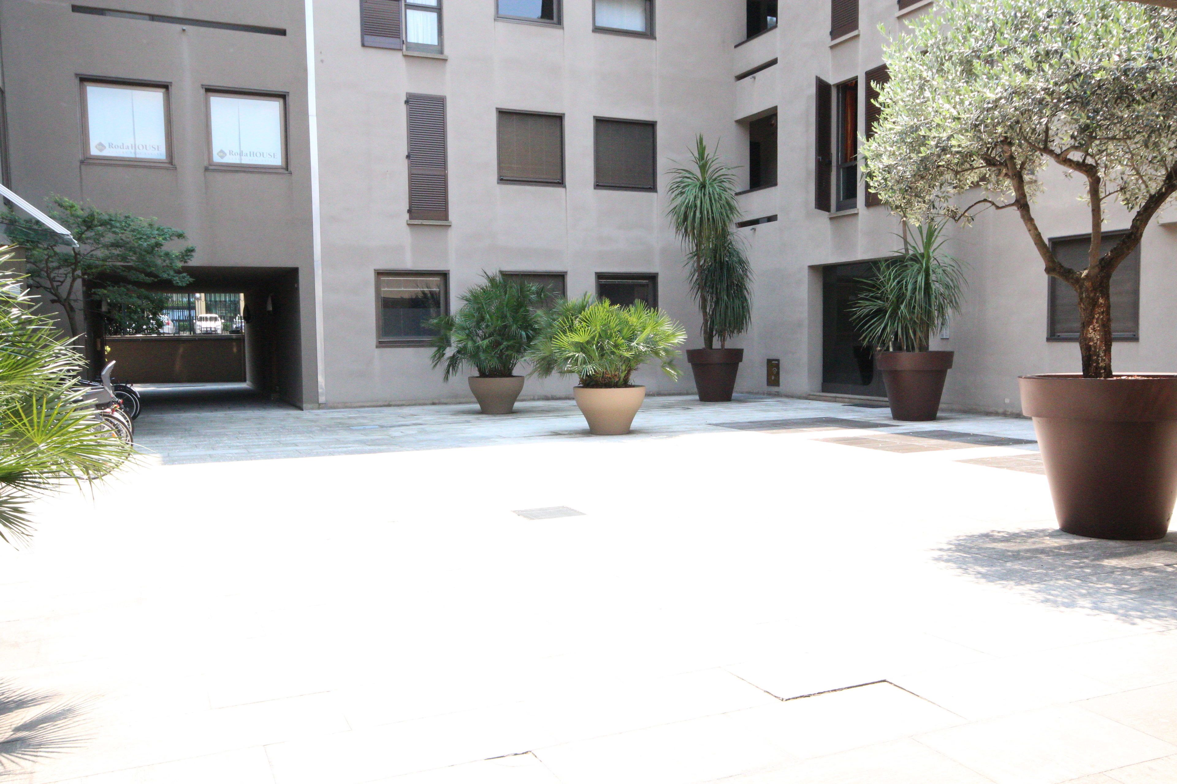 A courtyard with potted plants and a building with multiple windows.