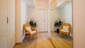 A hallway with two wicker chairs, a door, and potted plants. - Victoria Apartment (Como)