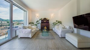 A spacious living room with a glass coffee table, white sofas, and a fireplace. - Victoria Apartment (Como)
