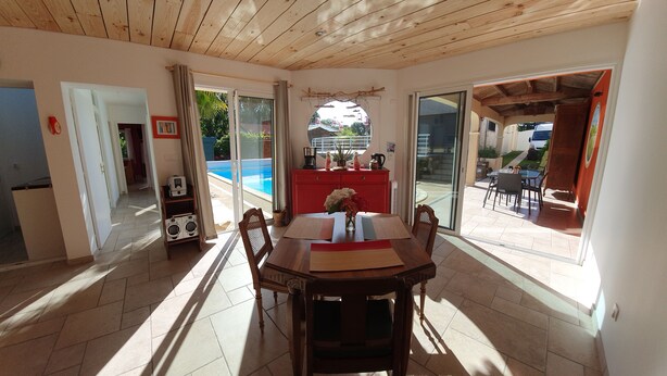Un comedor con una mesa, sillas, un armario rojo y vistas a una piscina a través de puertas de cristal.