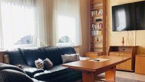 Een moderne woonkamer met een bank, een salontafel, een boekenkast en een televisie.