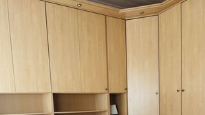 Een slaapkamer met een bed, een houten garderobe en ingebouwde planken.